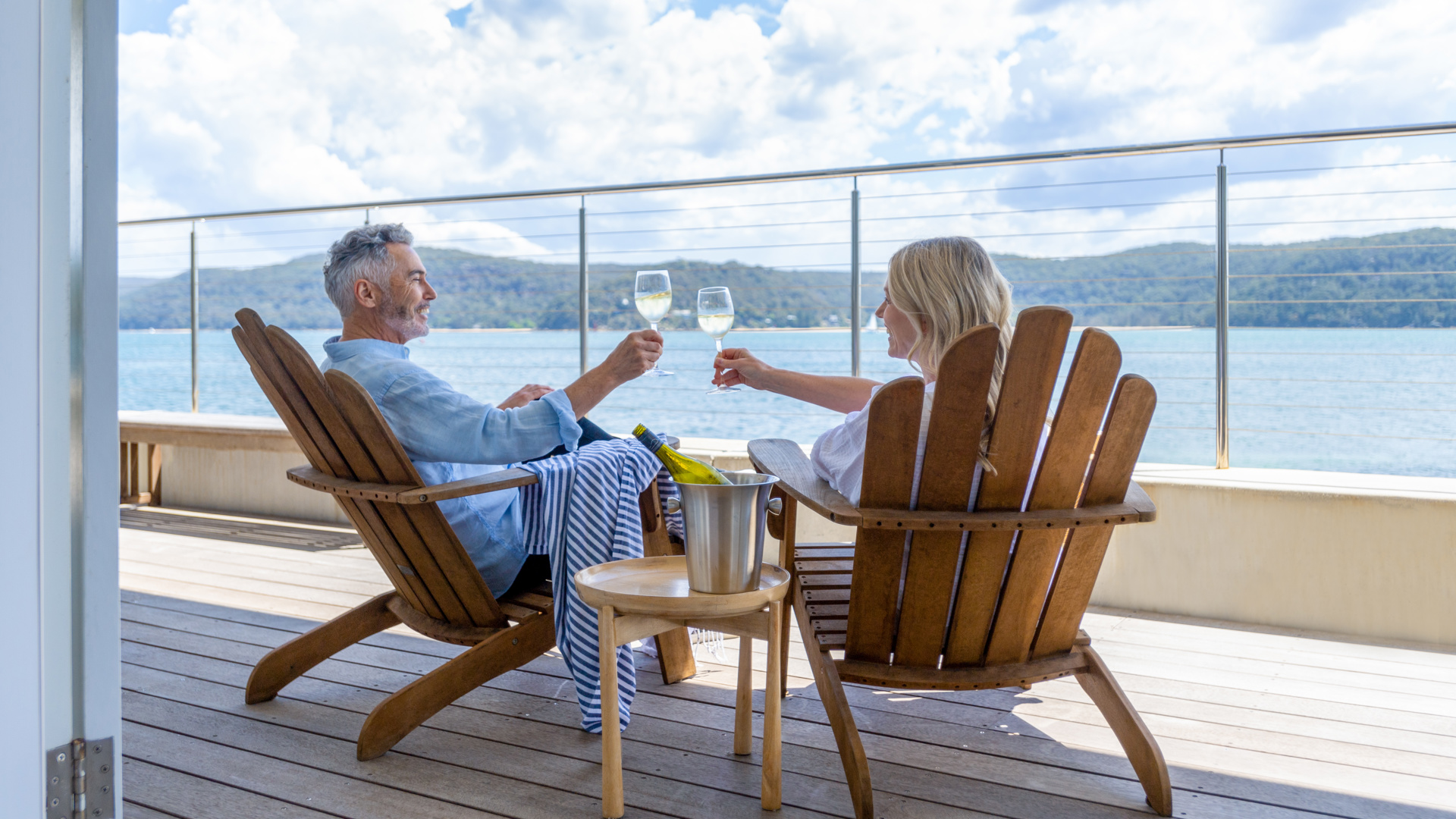 Couple relaxing and drinking wine on deck chairs - Image credit: Getty Images