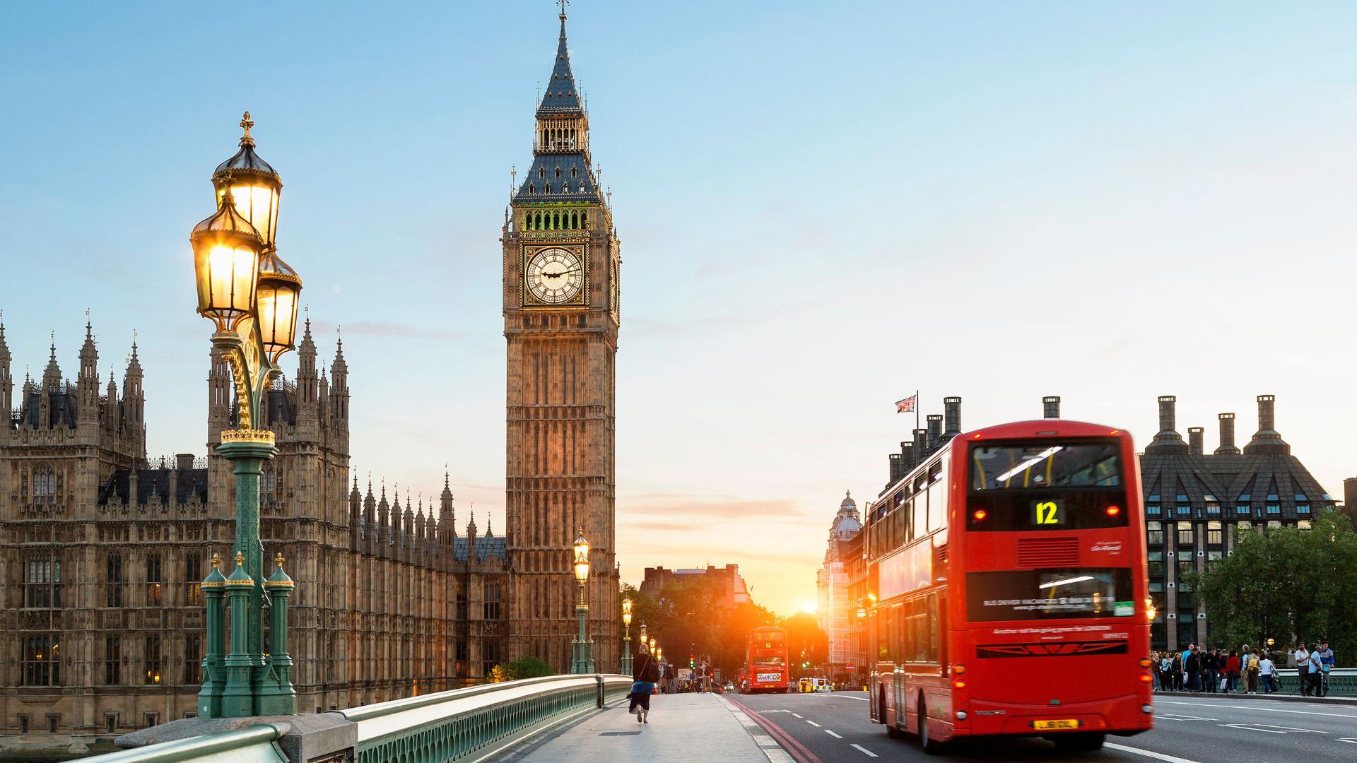 A red double-decker bus passing by Big Ben