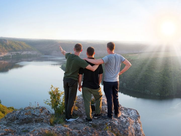 Three Friends On Cliff Looking At View