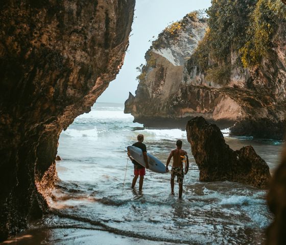 Two men walking into the surf in Bali